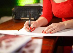 woman in red shirt signing book