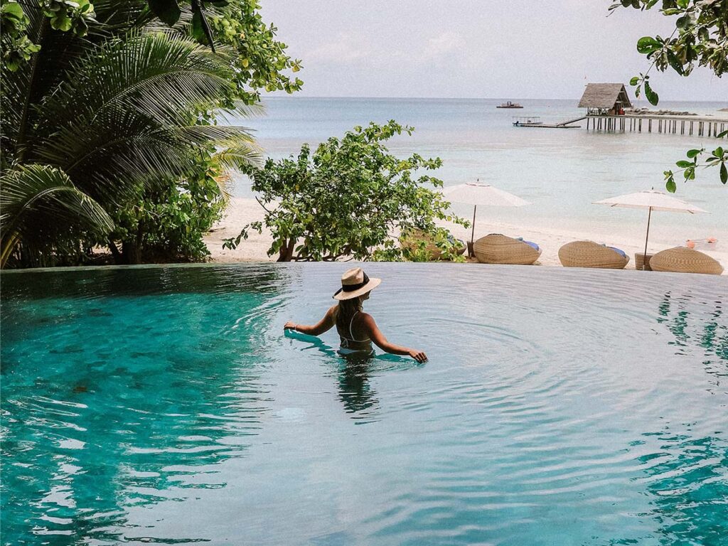 A woman in a hat is swimming in the pool