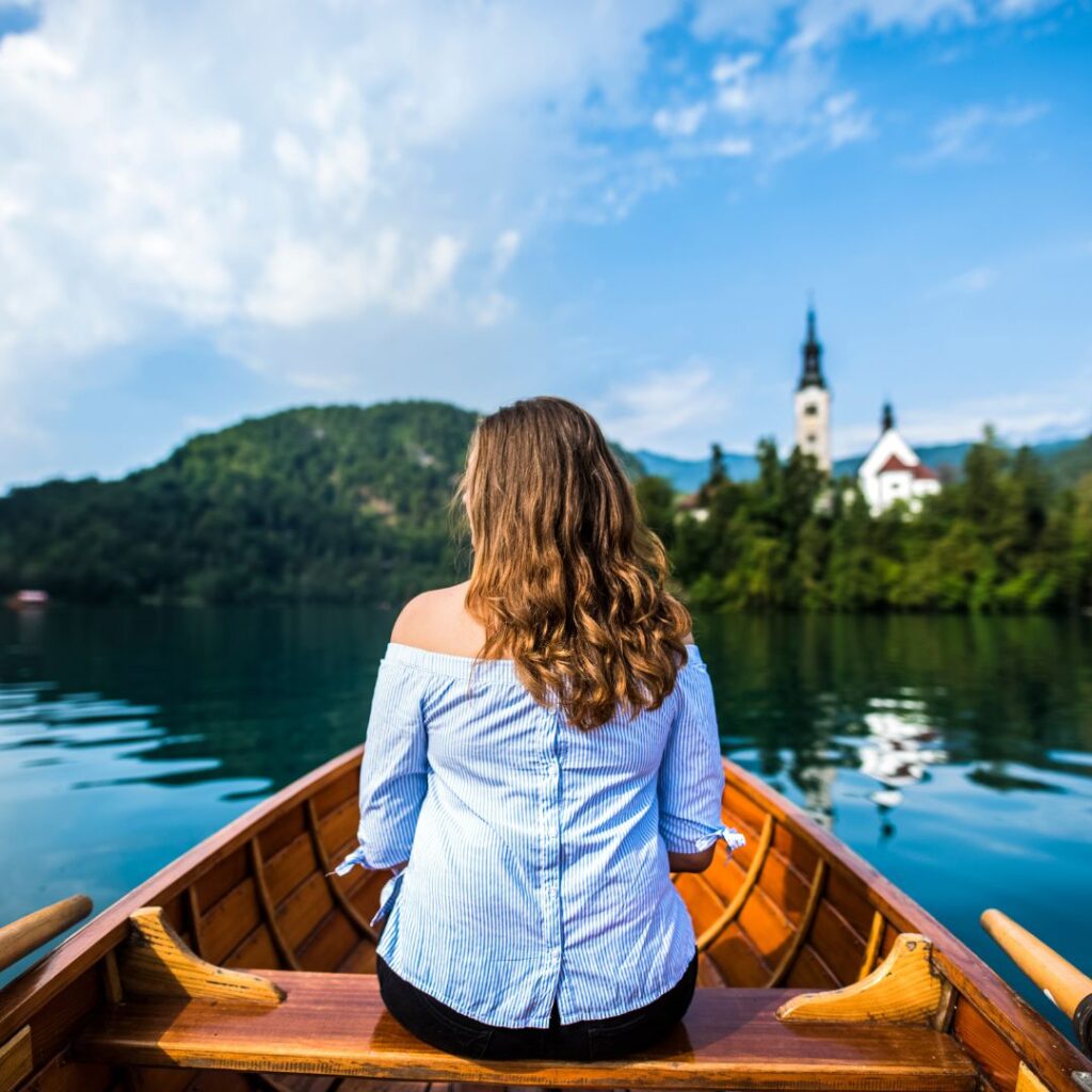 A woman sitting on the back of a boat in the water.